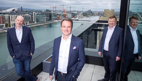 An image of Ocuco's CEO, Leo Mac Canna, on a balcony with two men standing behind him.