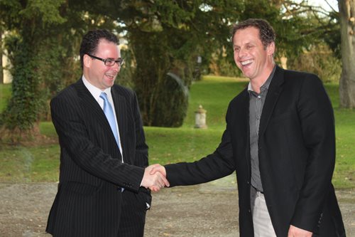 A photo of Leo Mac Canna shaking hands with another man. Both men appear to be smiling in the image.