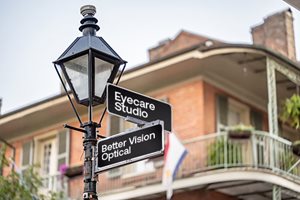 An image of a lamp post with two signs pointing in different directions. One sign points straight and says: 'Better Vision Optical'. The other sign posts right and says: 'Eyecare Studio'.