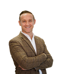 A photo of Dermot Walsh. He has light brown hair and is wearing a white shirt with a brown blazer.