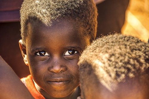 An image of a child African descent wearing an orange shirt.
