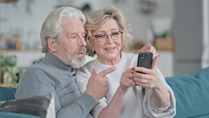 An image of a woman and a man. The woman holds up her phone up and the man next to her is also looking at the screen.