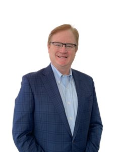 A photo of Jim McGrann. He is wearing a blue shirt and navy blazer.