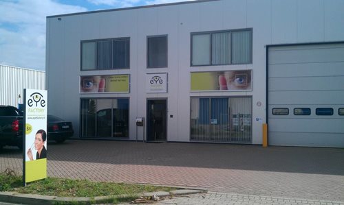 A photo of a white office building. In front of the building is a banner for a company called 'eye'.